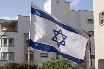 National Israeli flag waving in the background of a typical apartment building.