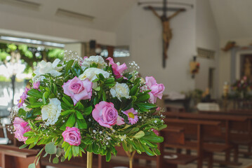 Bouquet of flowers with religious images in the background. Interior of a church.