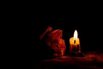 Candle flame and rose in the dark, mourning and sadness