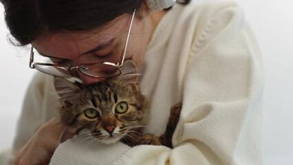 A teenage girl hugs and kisses a cat.