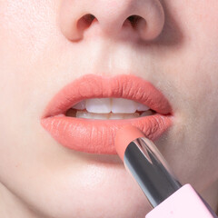 Naklejka premium Closeup of woman applying light pink lipstick