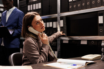 Inspector explaining police report using landline phone, working overtime at criminal investigation...