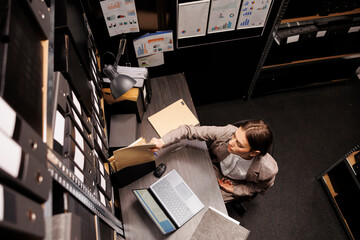 Top view of police officer typing criminal case report on laptop computer, analyzing crime scene...