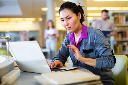 Asian woman student studying at the university by correspondence studies in the library on a laptop while preparing for ..the exam