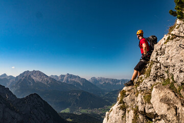 Male climber on the top of the mountain looking at the landscape, with helmet