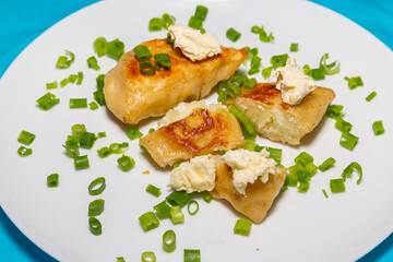 Fried pieroguis Ukrainian traditional food, on white plate on tablecloth decorated with typical...