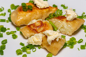 Fried pieroguis Ukrainian traditional food, on white plate on tablecloth decorated with typical...