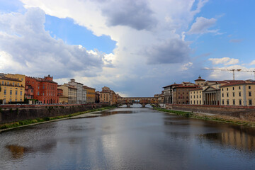Häuser am Arno und Ponte Vecchio unter malerischen Wolken in Florenz