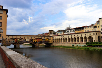Naklejka premium Häuser am Arno und Ponte Vecchio unter malerischen Wolken in Florenz