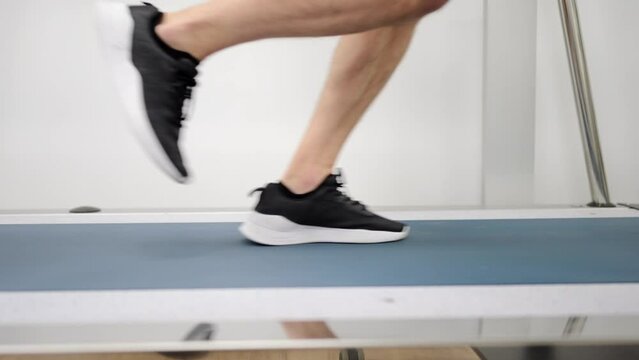 Close-up video of the legs of a man running on a treadmill during a cardiac stress test