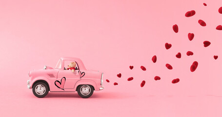 Love composition made of Teddy bear and Pink toy car that leaves a mark in the cloud of the heart on pink background. Minimal concept of Valentine's Day or love. Creative art, minimal aesthetics.