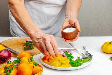 A woman is preparing a tomato salad. Ripe vegetables, herbs, aromatic spices, olive oil