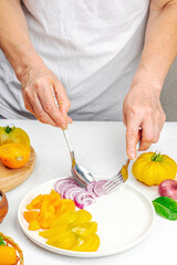 A woman is preparing a tomato salad. Ripe vegetables, herbs, aromatic spices, olive oil