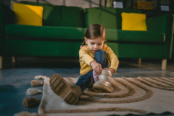 girl toddler child puts on her own boots in the winter at home