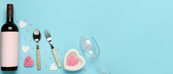 Beautiful table setting for Valentine's Day with bottle of wine on blue background with space for text