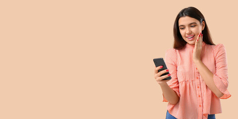 Happy woman using mobile phone on beige background with space for text