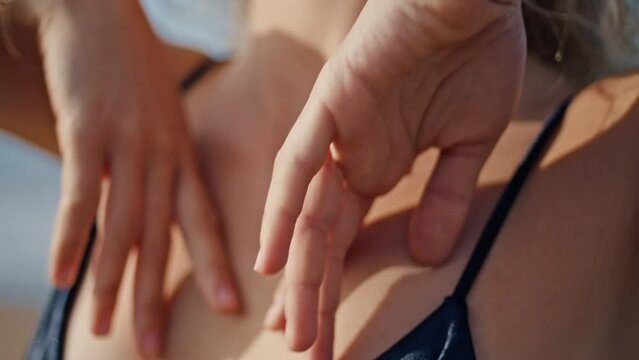 Tender woman hands touching tanned skin at collarbone area on nature close up. 