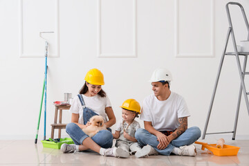 Happy family in hardhats sitting on floor during repair of their new house