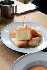 Pieces of lightly toasted white bread in white plate on wooden table. Morning breakfast. Coffee and dessert concept.