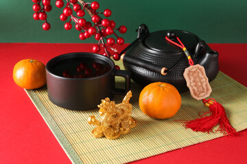 Traditional tea setup with golden dragon figurine and mandarins on green background. Chinese New...