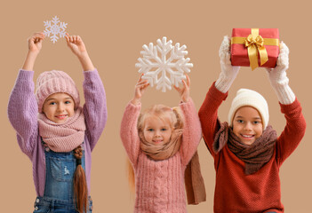 Cute children in winter clothes on beige background
