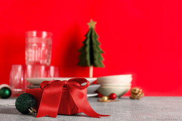 Gift box with decorated Christmas table setting on red background