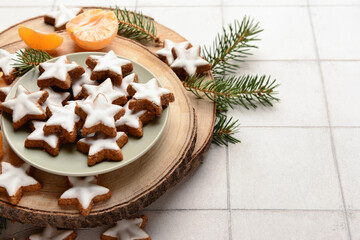 Christmas composition with delicious stars shaped cookies, fir branches and mandarin on white tile background