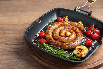 Delicious homemade sausage with garlic, tomatoes, rosemary and spices in grill pan on wooden table,...