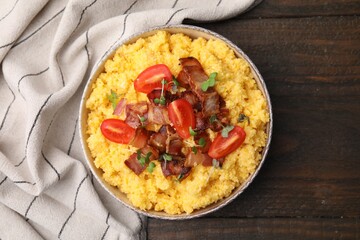 Tasty cornmeal with tomatoes, bacon and microgreens in bowl on wooden table, top view