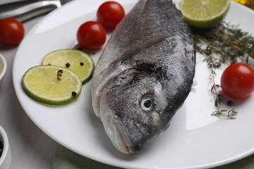 Raw dorado fish, lime slices, tomatoes and thyme on table, closeup