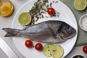 Raw dorado fish, lime, tomatoes and thyme on light table, flat lay