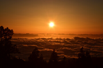 Słońce tuz przed zachodem tuż ponad chmurami w parku Teide na Teneryfie