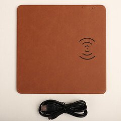 Charging the smartphone with leather wireless charger on desk. Light brown color leather charger pads. Wireless mousepad, Charger pad. Closeup, top view, no people. Concept shoot. isolated