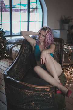 Gorgeous woman with bright multi-colored hair posing in blue lingerie near a Christmas tree