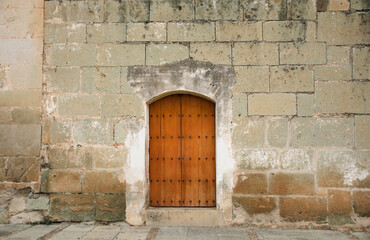 Fototapeta na wymiar Beautiful green quarry façade and old wooden door, in Santo Domingo, Oaxaca, Mexico.