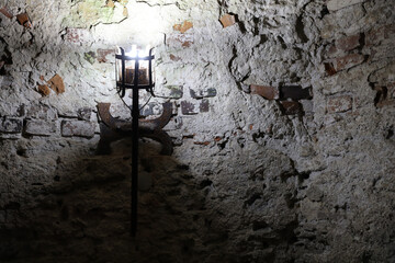 Lighted medieval castle torch hanging on a stone wall, vintage objects and background
