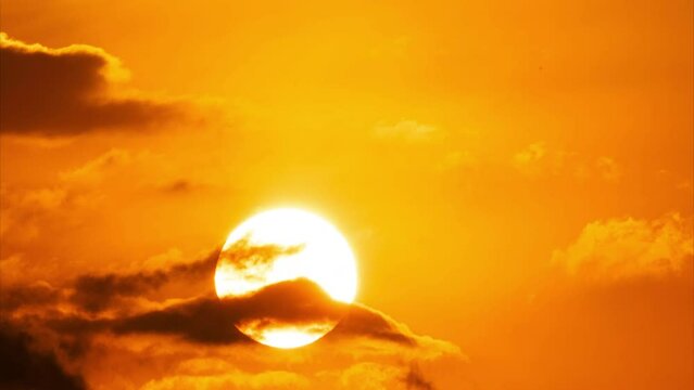 Beautiful nature morning with orange, yellow sunshine and fluffy clouds. Time lapse of a beautiful dramatic sky with a big sun at sunrise.