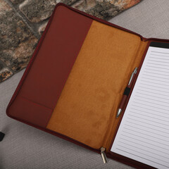 Leather Zipper Portfolio. Concept shot, top view, flap portfolio in brown colors and leather pen. Custom background flap portfolio view. Zipper portfolio on desktop.
