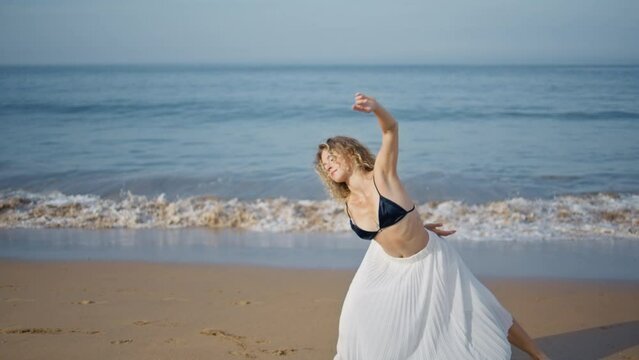 Woman making dance performance on picturesque ocean beach. Sensual girl dancer