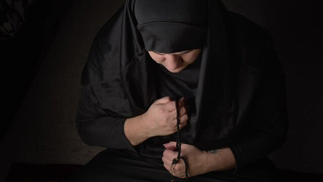 Young Muslim woman in black prayer clothes and headscarf