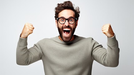 Handsome man with beard wearing casual sweater and glasses very happy and excited doing winner gesture with arms raised over white background.