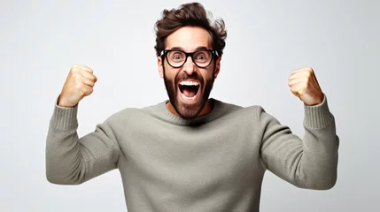 Foto op Canvas Handsome man with beard wearing casual sweater and glasses very happy and excited doing winner gesture with arms raised over white background. © Oulaphone