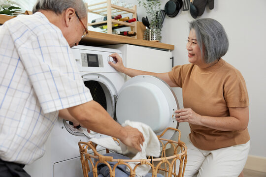 senior woman and her husband doing laundry together with washing machine at home