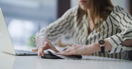 Cloth, phone and woman cleaning in the office for hygiene, health and wellness sanitation. Hands, technology and closeup of female person wipe cellphone to prevent germs, dust or dirt in workplace.