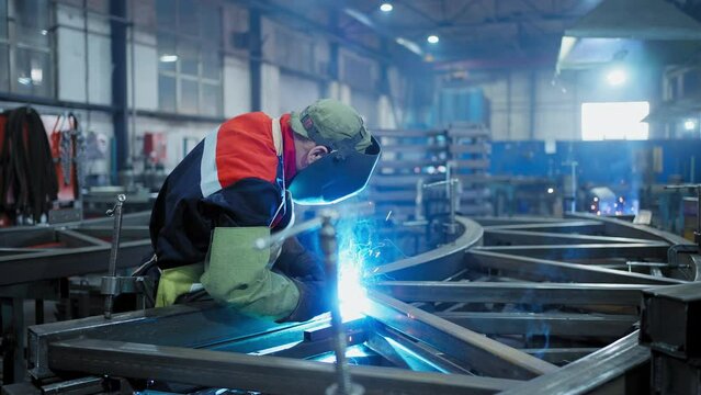 Professional Welder Working at factory facility. Factory workshop with a male technician welding in it