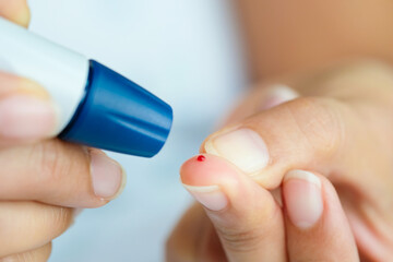 Doctor checks diabetes on woman's hand, checking diabetes and high blood sugar levels with digital blood sugar tester. .Health care and medical concept	