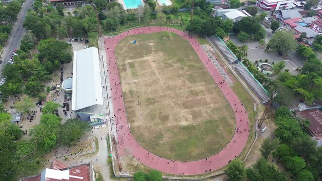 Aerial view of people running at the GOR Nani Wartabone, Gorontalo City. Group of people on the running track, the football field, or the soccer field. 
