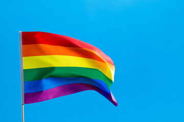 Rainbow flag waving on blue background
