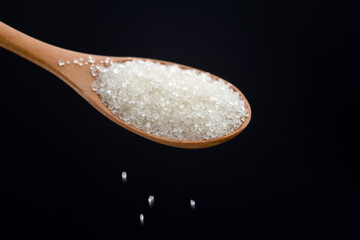 Sugar crystals falling out of wooden spoon