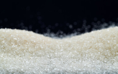 Pile of white sugar crystals on black background